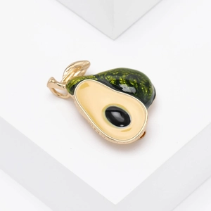 Creative cartoon avocado brooch with green enamel and gold plating on white surface