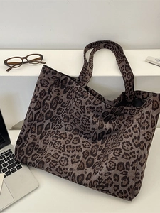 Large leopard print faux suede tote bag with wide straps shown with a laptop on white steps