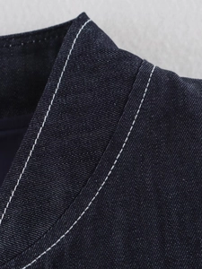 Detailed close-up of dark blue denim collar featuring high-contrast white topstitching