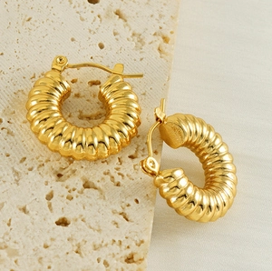 Detail of 18k gold plated stainless steel croissant hoop earrings on beige stone