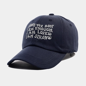 Close-up of white motivational embroidery on a navy blue cotton canvas baseball cap