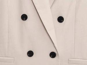 Gros plan détaillé du blazer beige à double boutonnage avec tissu sergé et boutons ronds