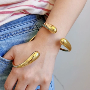 Gouden lava-druppelvormige open manchetarmband met glanzende afwerking voor een moderne look