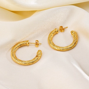 Twisted geometric hoop earrings in 18K gold plating on elegant beige silk fabric