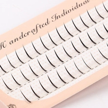 Macro shot of handcrafted individual black eyelash clusters on pink tray packaging