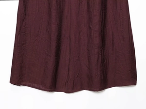Close-up of the pleated hem on a dark burgundy two-piece vest and skirt set for women