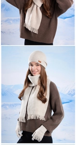 Detail of winter knitted set featuring cream white beanie, scarf with tassels and gloves