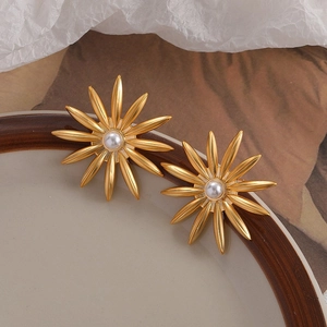 Elegant gold sunflower earrings with pearls on a ceramic plate, luxury minimalist style