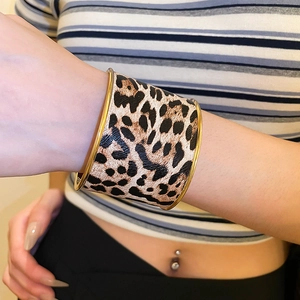 Close-up of wide leopard print leather cuff bracelet with polished gold metal edges