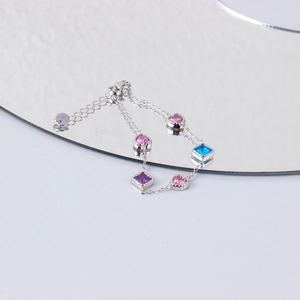 Close-up of heart and square colored zircons on silver stainless steel chain with mirror