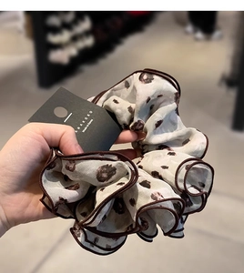 Detail of oversized floral chiffon scrunchie with brown wavy edges and leopard pattern