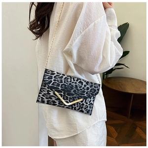 Detail view of the leopard print texture and gold V-shaped buckle on an envelope bag