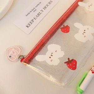 Detail of glitter pencil case with red zipper, strawberry prints and heart charm