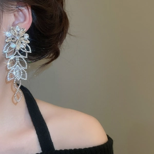Détail de boucles d'oreilles fleur argentée avec longues pampilles en strass sur un mannequin