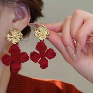 Elegant gold and red floral drop earrings worn by a model in a close-up profile shot