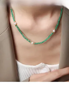 Détail d'un collier en perles de pierre verte et perles blanches sur un blazer