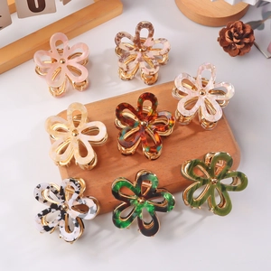 Elegant acetate flower hair clips in various colors displayed on a wooden base