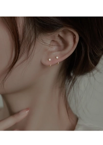Close-up of minimalist gold zircon stud earring with U-shaped curve design on ear