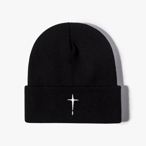 Close-up of black knitted beanie featuring white cross embroidery and ribbed texture
