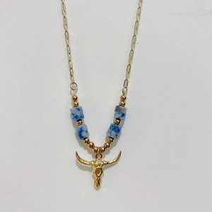 Detailed close-up of golden bull skull pendant with blue and white stone beads