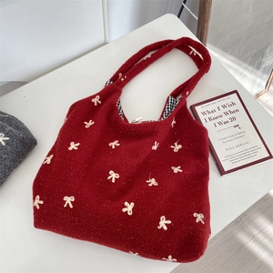 Detail of red knit tote bag with beige bow embroidery and black gingham lining
