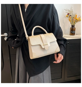 Beigefarbene Umhängetasche mit Krokostruktur und Golddetails an einem Model