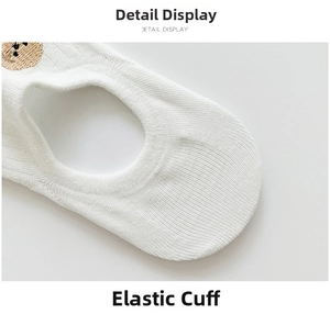 Macro detail of the elastic ribbed cuff and brown bear embroidery on white cotton socks