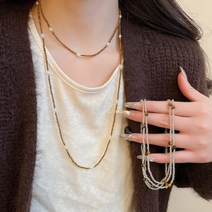 Close-up of layered stainless steel beaded tiger eye necklace on brown sweater