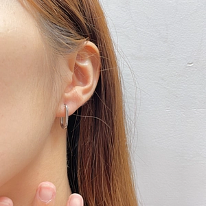Close-up of minimalist silver U-shaped geometric earring on female model ear