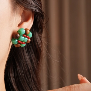 Detail of handmade ethnic earrings with green beads and brown wood beads on model
