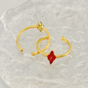 Detail of gold-plated clover rings with vibrant red and green marquise-cut crystals