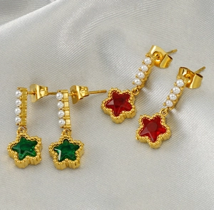 Détail gros plan des boucles d'oreilles étoile dorées avec perles et pierres rouges et vertes