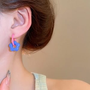 Close-up of vibrant pink and blue flower hoop earrings on model for a trendy look