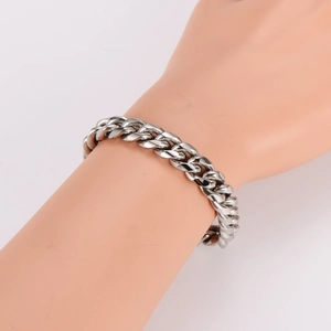 Industrial style silver stainless steel curb chain bracelet worn on a model's wrist