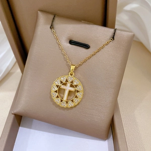 Detail of gold cross pendant with heart-shaped crystal frame on beige jewelry stand