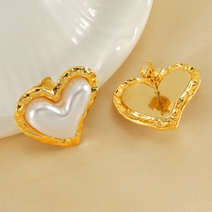 Boucles d'oreilles cœur en perle dorée élégantes présentées sur soie et coquillage