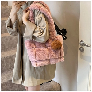 Close-up of pink fuzzy woven tote bag with a cute brown bear charm on a model