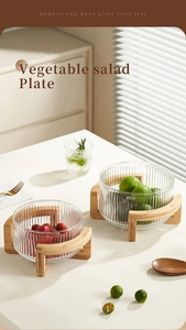 Close-up of glass fruit bowls with vertical stripes and curved bamboo wood base