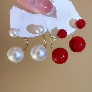 Dettaglio orecchini a doppia perla a forma di C in bianco perla e rosso laccato con oro