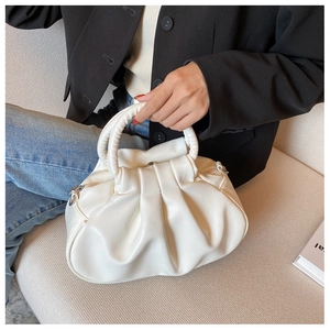 Detail of white pleated cloud bag featuring a round handle and silver zipper closure