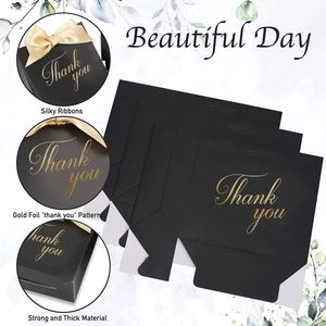 Détail du sac cadeau noir avec lettrage doré et rubans en soie couleur champagne élégant