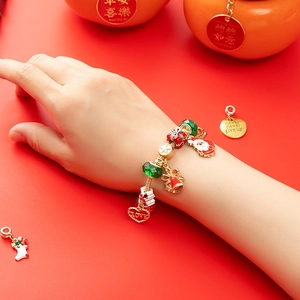 Christmas DIY charm bracelet with festive beads and Santa pendants on red background