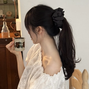 Close-up of a black textured fabric scrunchie worn on a ponytail for elegant hair styling