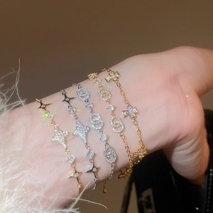 Details eleganter Gold- und Silberarmbänder mit Stern- und Kreuzanhängern und Zirkonia-Steinen