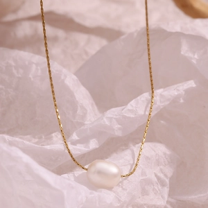 Detailed close-up of a white oval pearl pendant on a minimalist 18K gold-plated chain