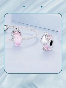 Macro detail of S925 silver cat charm with pink glass bead on a mesh bracelet