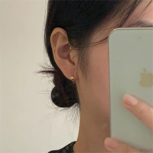Detailed view of elegant gold four-point star stud earrings worn for daily style