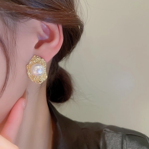 Close-up of vintage flower pearl earrings with textured gold hammered metal borders