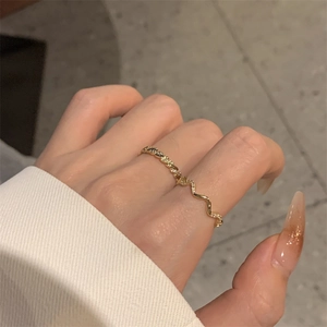 Close-up of gold-plated wavy ring featuring micro-paved cubic zirconia accents