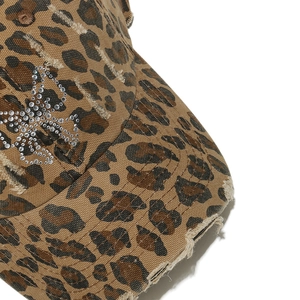 Détail de la casquette léopard avec papillon en cristal et texture effet usé